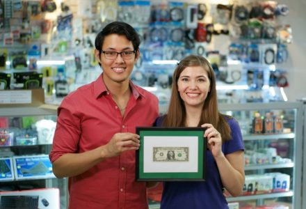 Small business owners holding framed dollar bill