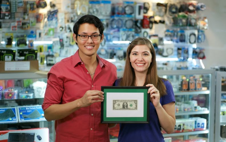 Small business owners holding framed dollar bill